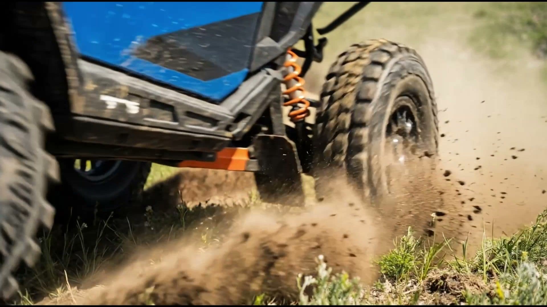 RZR rear wheel tearing through dirt — extreme close-up