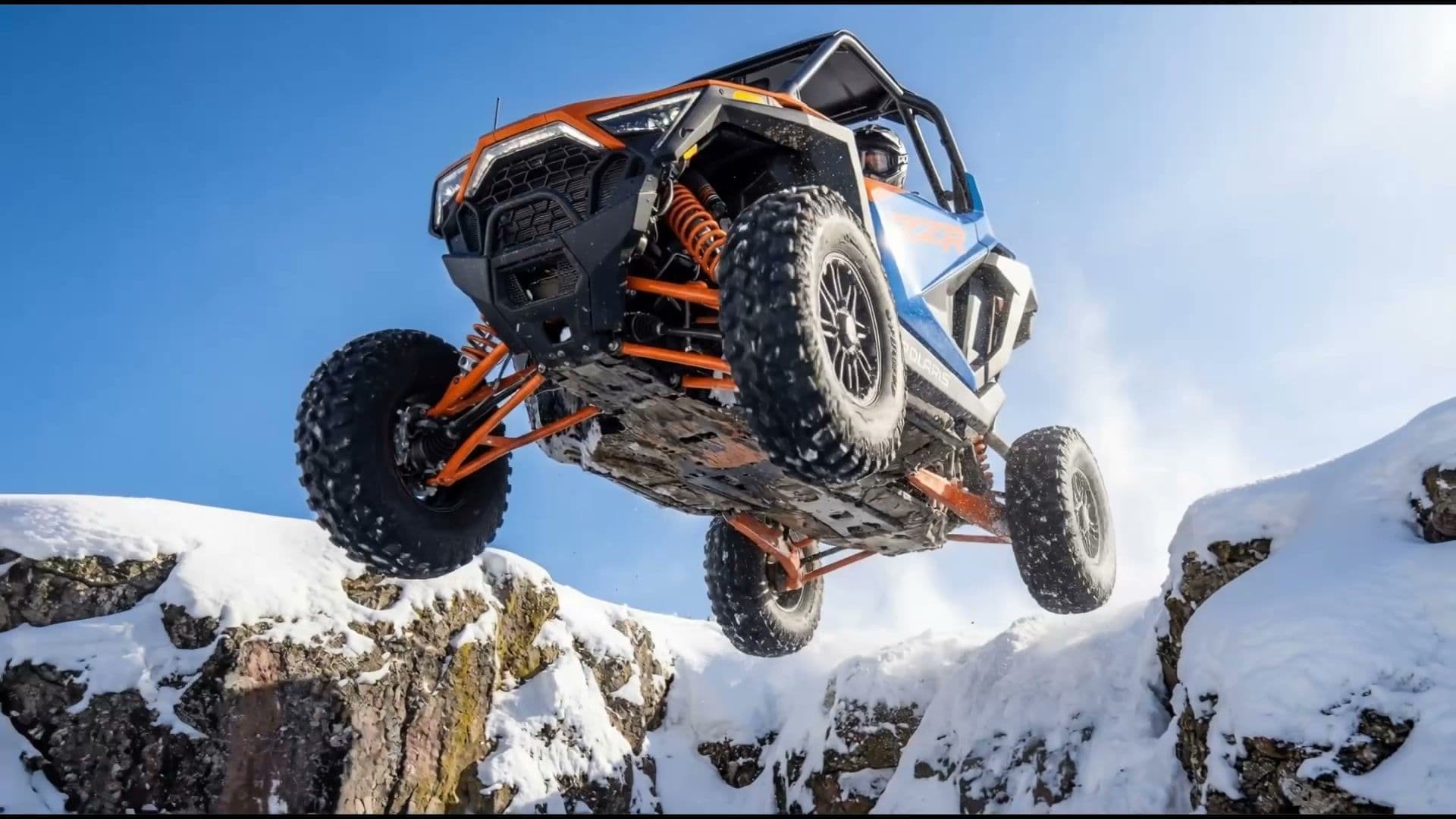 Polaris RZR catching air on snow-covered rock